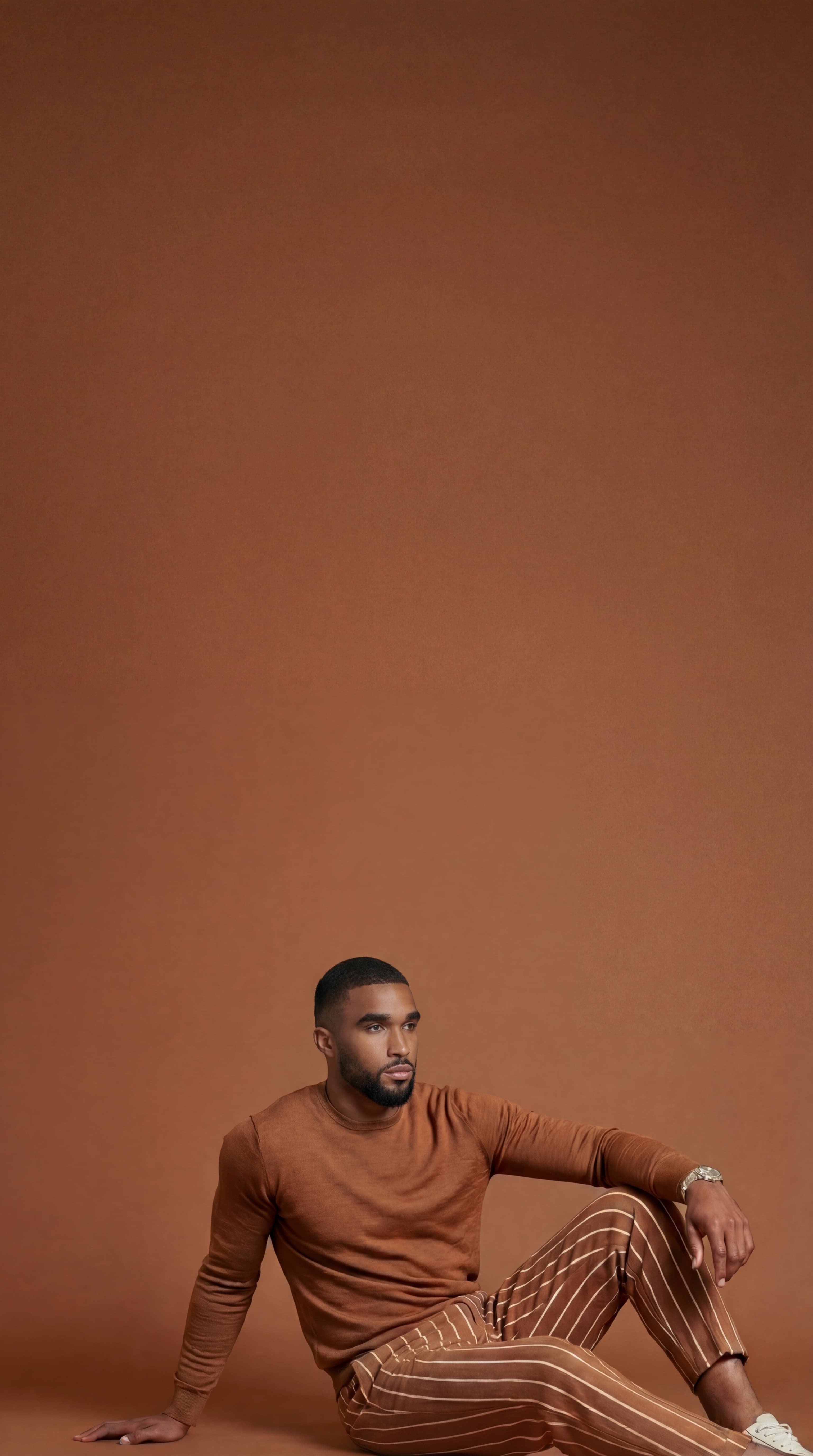 A Black male estetiq model seating confidently